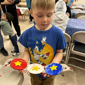 A child holding an arts and crafts project that he made.