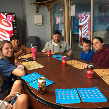 Family members sitting around a table with bingo cards and drinks.