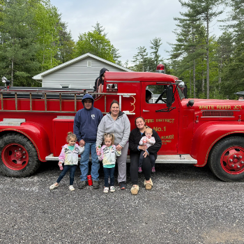 A family of six posign in front of Friendly Beaver Campground's Fire Truck.