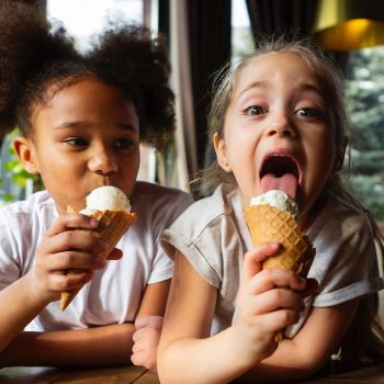 Two girles each eating an ice cream cone.