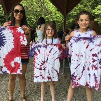 Three family members holding up Tie Dye shirts that they made.
