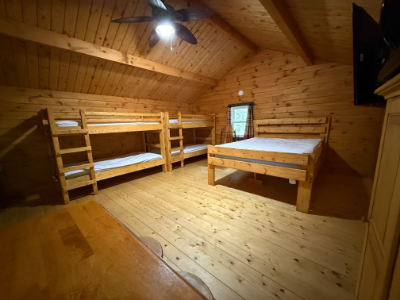 Picture of the inside of a cabin showin the queen sized bed, and bunk beds.
