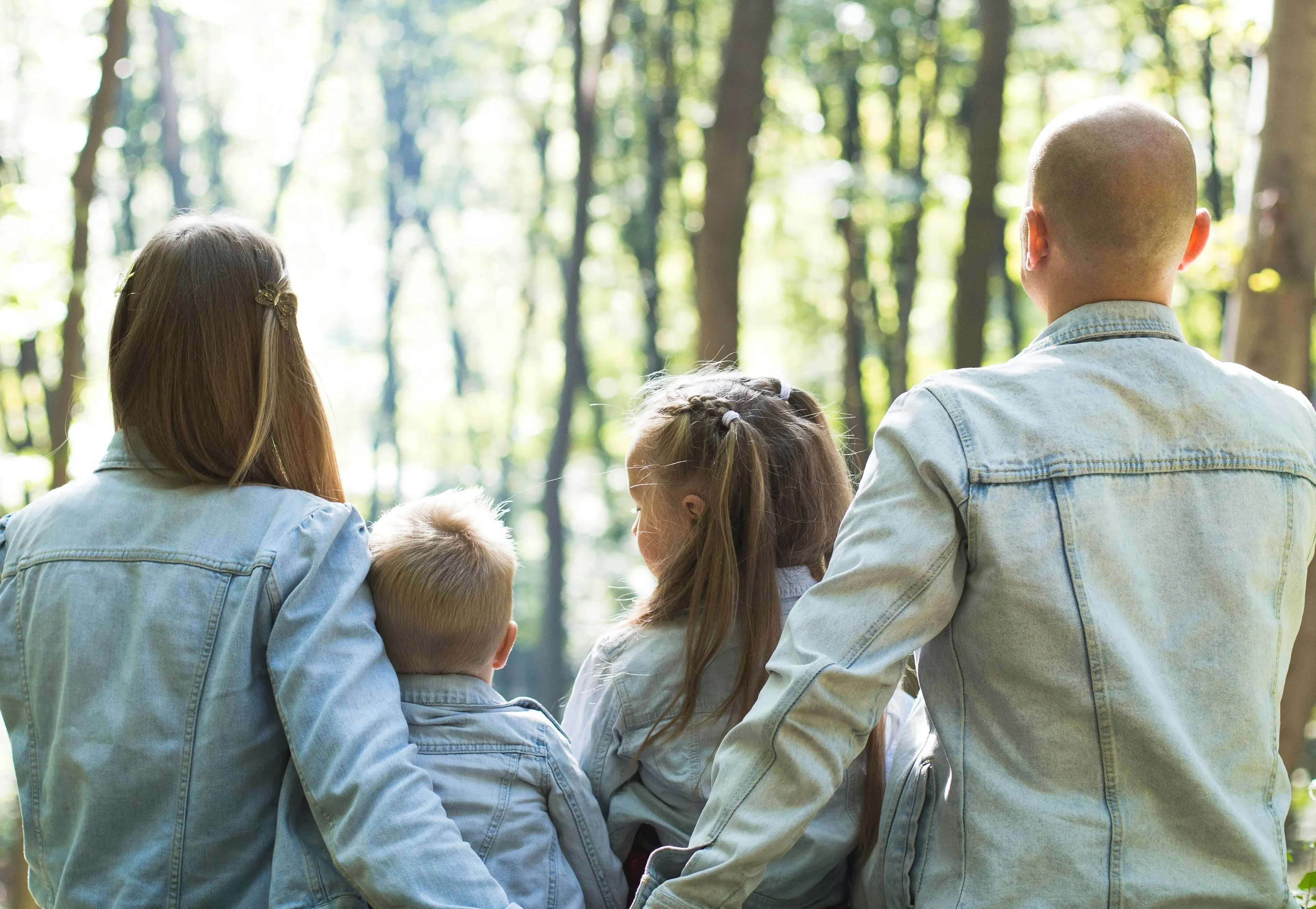Mother, father, daughter, and son facing a brightly lit woods