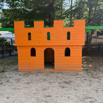 Wooden representation of a castle painted orange meant for children to play on.
