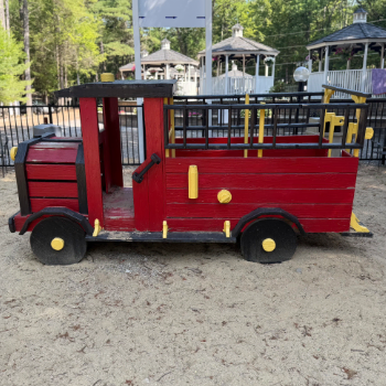 Wooden representation of a fire truck painted red and black meant for children to play on.