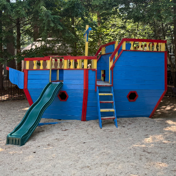 Wooden representation of a pirate ship painted blue, red, and yellow meant for children to play on.