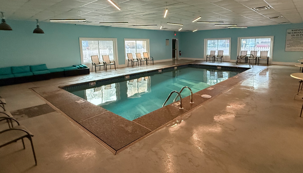 An indoor pool with windows and chairs around it.