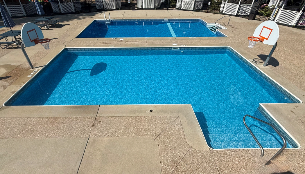 Outdoor pool with stairs and 2 basketball hoops.