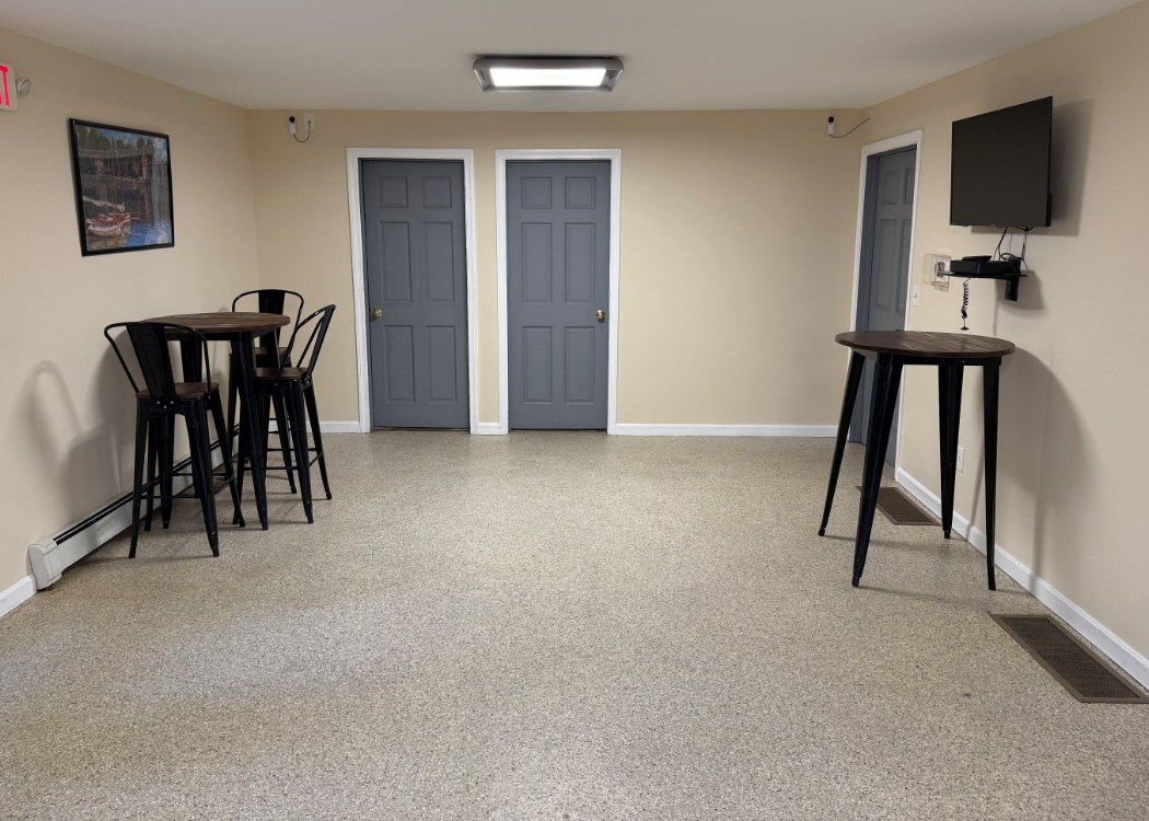 An area with tables, charis and a tv.