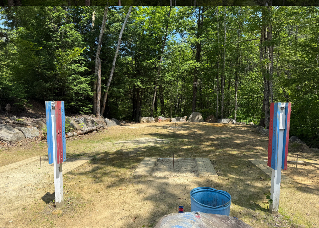 Outdoor horshoe pits with trees surrounding it.