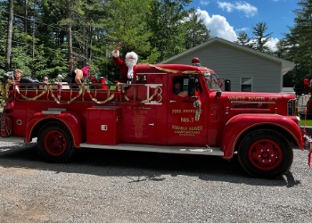 Red fire truck decorated for christimas with santa waving.